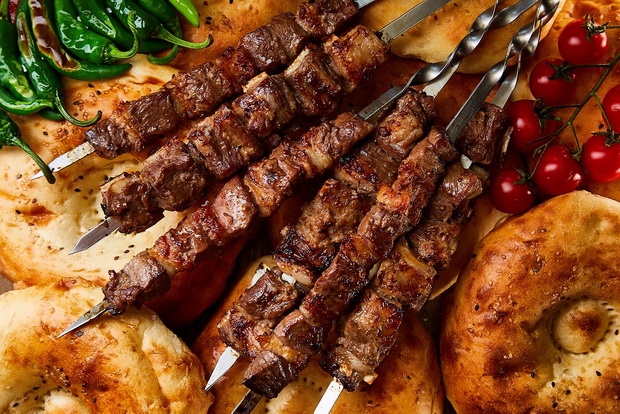 Charcoal-grilled lamb shashlik skewers served with vegetables and flatbread